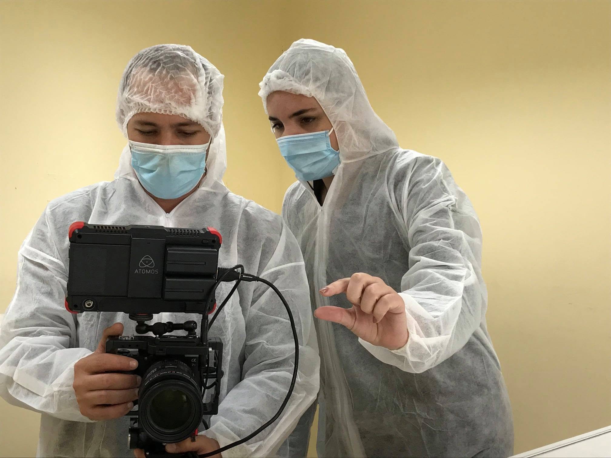 Diana y un colega revisan el monitor de una cámara con equipos de protección en laboratorio